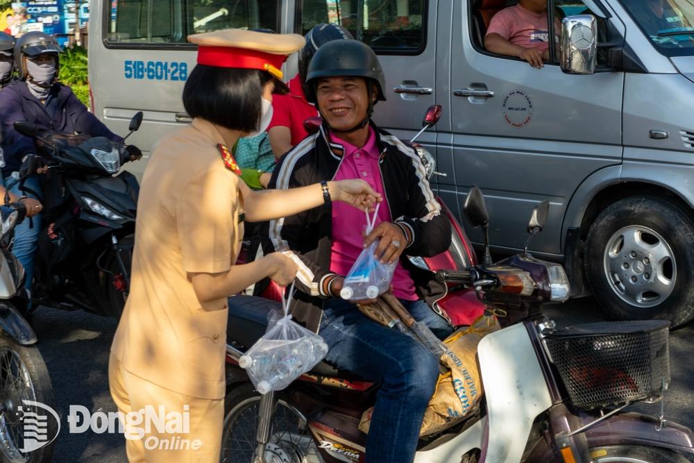 Người đi trên quốc lộ 1 (thành phố Biên Hòa) vui vẻ nhận nước suối và khăn lạnh do lực lượng Cảnh sát giao thông tặng. Ảnh: Lê Duy