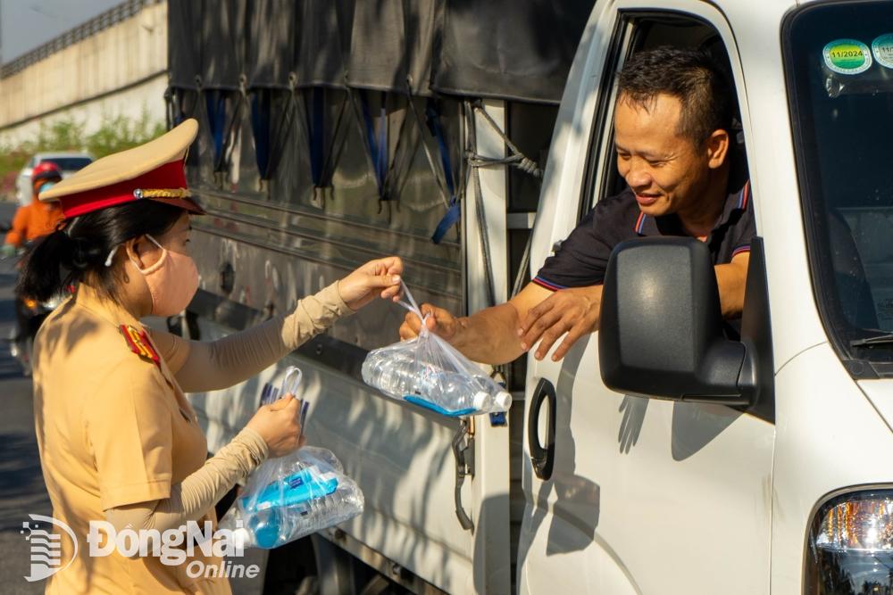 Lực lượng Cảnh sát giao thông phát nước suối và khăn lạnh giúp những tài xế xe tải di chuyển quá quốc lộ 1 (thành phố Biên Hòa) được tỉnh táo giữa thời tiết nắng nóng. Ảnh: Lê Duy