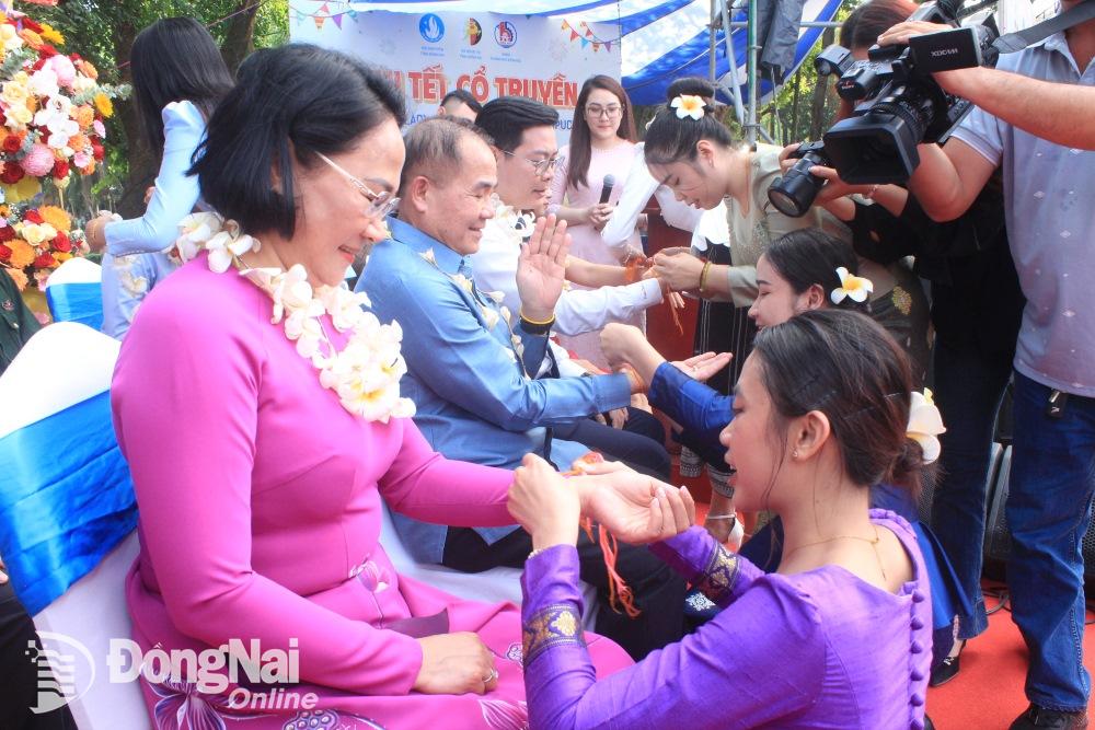 Sinh viên Lào, Campuchia thực hiện nghi thức buộc chỉ cổ tay tại chương trình họp mặt Tết cổ truyền. Ảnh: Nga Sơn