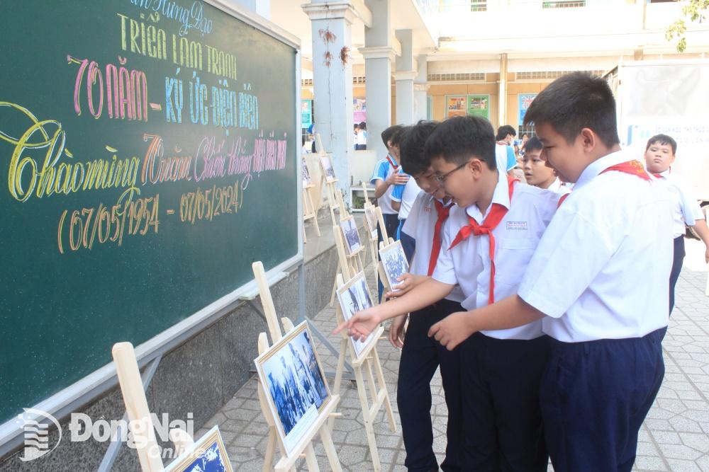 Các em học sinh Trường THCS Trần Hưng Đạo xem triển lãm hình ảnh được bố trí bên ngoài hội trường. Ảnh: Nga Sơn