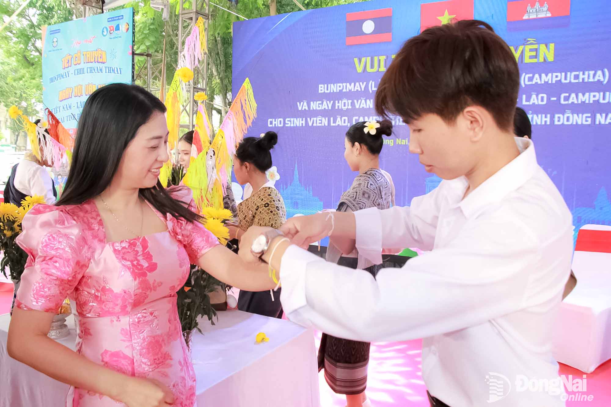 Lao and Cambodian students perform the traditional wrist-tying ritual to convey New Year wishes. Photo: Nga Son

