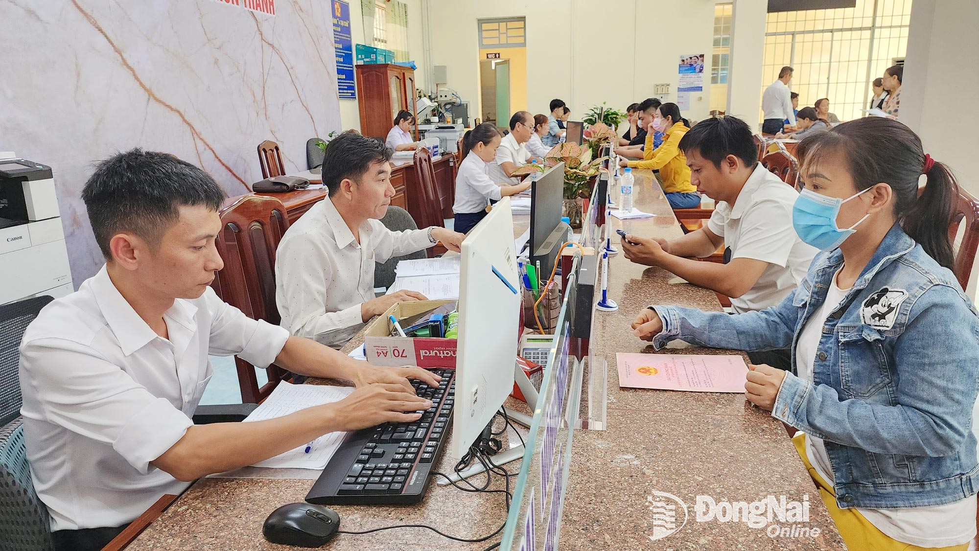 Người dân phường Chơn Thành được cán bộ, công chức hỗ trợ nộp hồ sơ trực tuyến. Ảnh: Ngân Hà