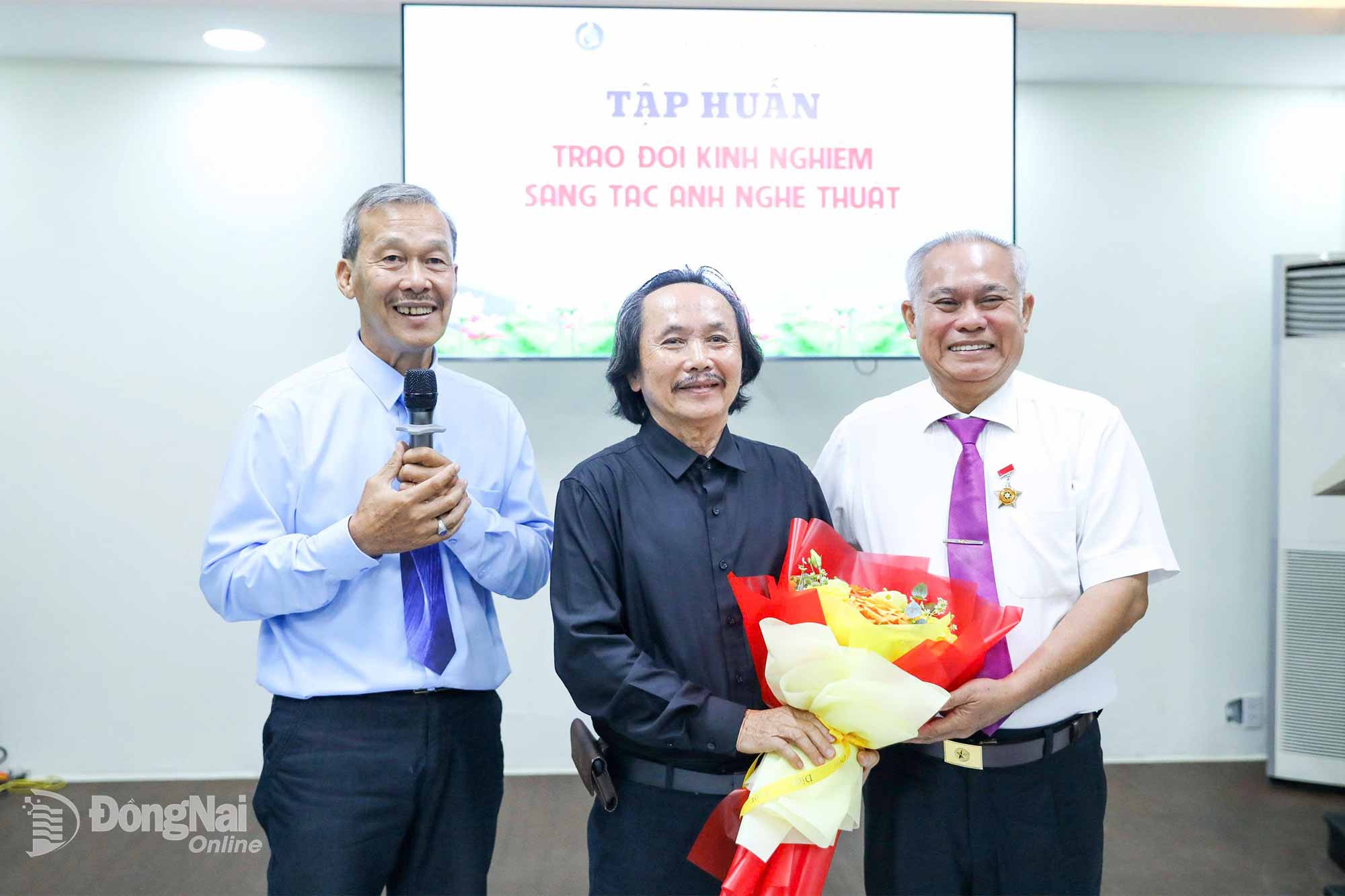 Đại diện Hội Văn học nghệ thuật Đồng Nai tặng hoa cho nghệ sĩ nhiếp ảnh Hoàng Quốc Tuấn (giữa) tại buổi giao lưu, chia sẻ về nhiếp ảnh năm 2026. Ảnh: Nguyễn Anh Trọng