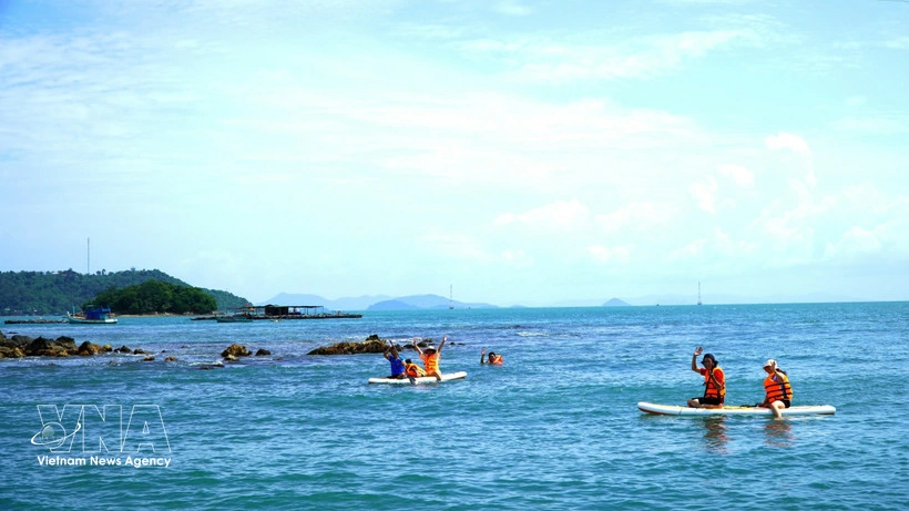 Tourists experience stand-up paddleboarding (SUP) along the coastal waters of the Hai Tac island. (Photo: VNA)