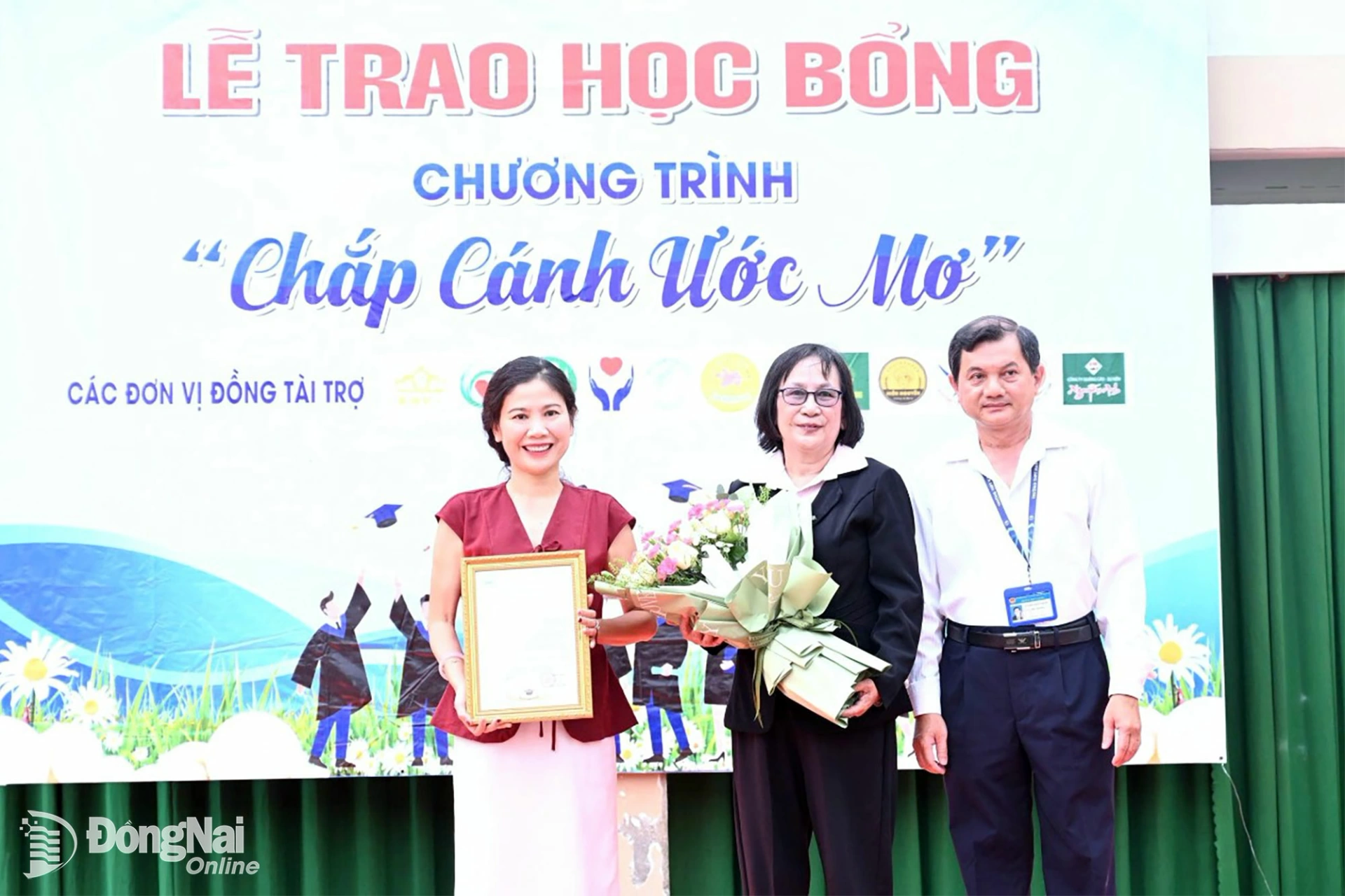 A representative of the Board of Principals of Nam Ha High School presents a letter of gratitude to Dong Nai Newspaper and Radio, Television, and presents flowers to the Provincial Study Promotion Association for their timely support of the schools disadvantaged students. Photo: Thu Hien

