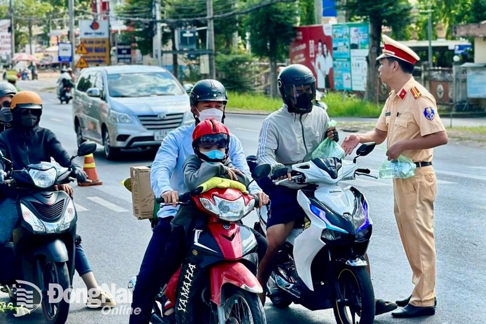 : Công an huyện Định Quán tặng nước, khăn lạnh cho người tham gia giao thông giữa trời nắng nóng. Ảnh: Văn Tuấn