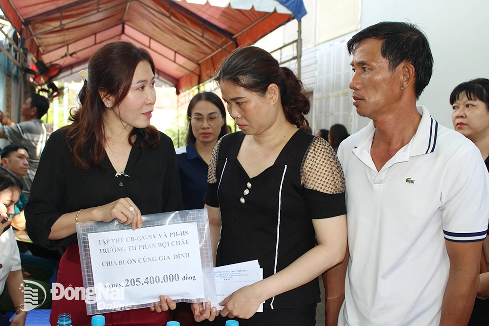 Đại diện Ban giám hiệu Trường Tiểu học Phan Bội Châu trao số tiền hơn 205 triệu đồng đến bố mẹ em Ngân. Ảnh: Khắc Thiết