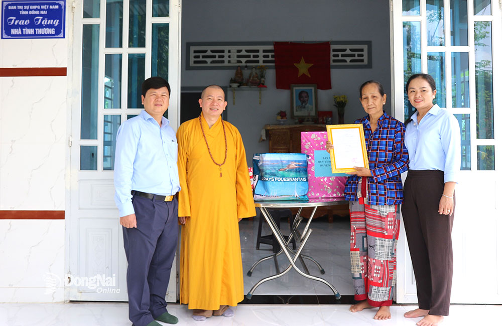 Đại đức Thích Thiện Trí, Phó thư ký, Chánh Văn phòng Ban Trị sự Giáo hội Phật giáo Việt Nam tỉnh, tặng quà cho một trường hợp tại huyện Định Quán trong ngày nhận quyết định bàn giao nhà kiên cố. Ảnh: S.Thao