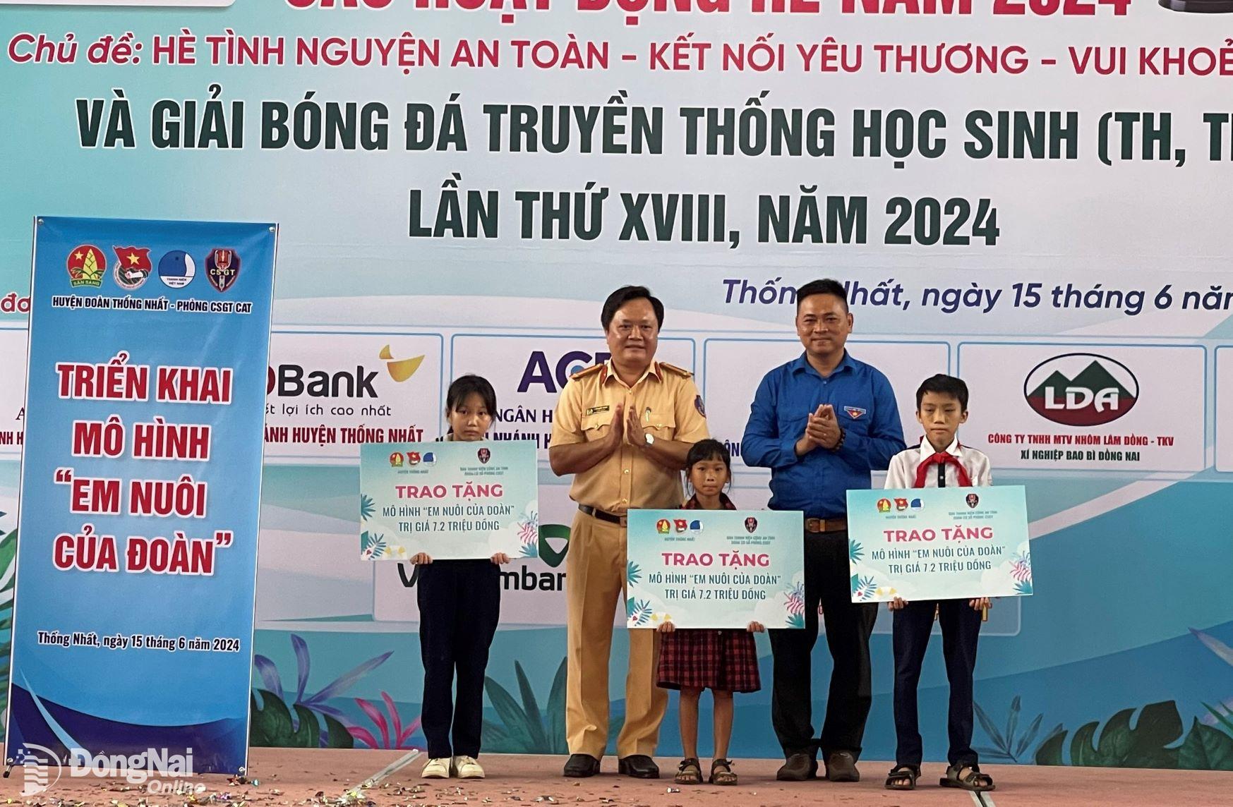 Các đại biểu trao bảng tượng trưng cho 3 học sinh tại huyện Thống Nhất được nhận hỗ trợ từ mô hình Em nuôi của Đoàn. Ảnh: Ban Thanh niên Công an tỉnh cung cấp