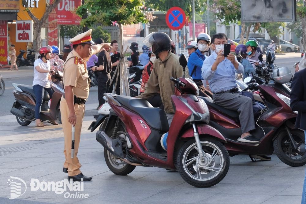 Lực lượng Cảnh sát giao thông nhắc nhớ phụ huynh đậu xe đúng vị trí trước khu vực Trường trung học phổ thông Ngô Quyền (phường Trung Dũng). Ảnh: Đăng Tùng
