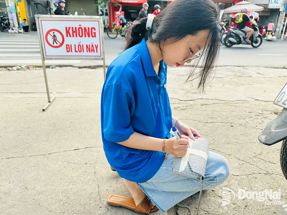 Thanh niên tình nguyện Trường trung học phổ thông Tam Hiệp giữ giùm túi xách cho thí sinh dự thi. Ảnh: Hạnh Dung