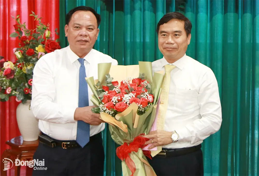 Quyền Chủ tịch UBND tỉnh Võ Tấn Đức trao quyết định và tặng hoa chúc mừng Quyền Chủ tịch UBND huyện Nhơn Trạch Nguyễn Thế Phong. Ảnh: Sông Thao
