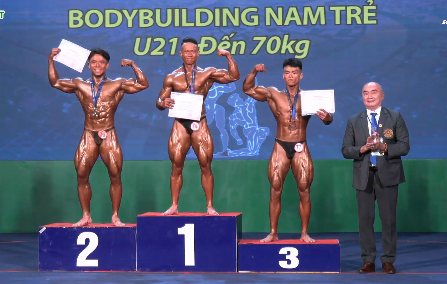 Vận động viên Phan Hùng Minh (Đồng Nai) trên bục nhận huy chương vàng hạng cân đến 70kg lứa tuổi U.21. Ảnh chụp màn hình