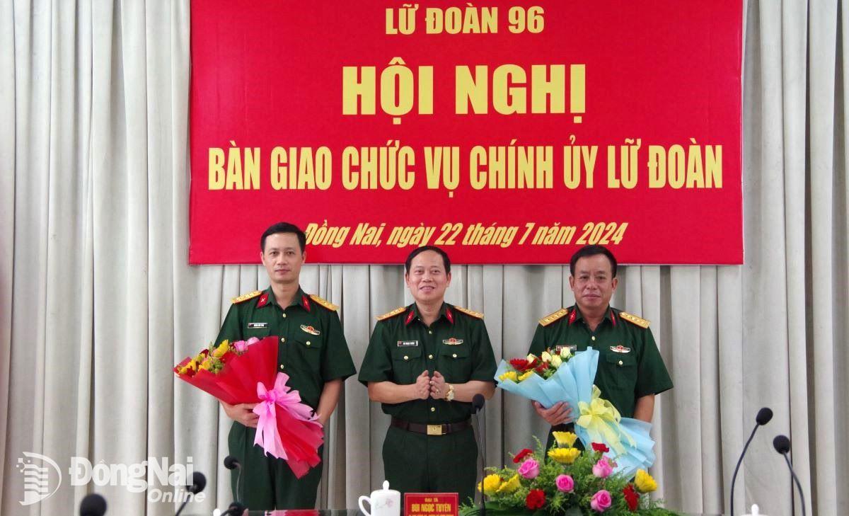 Đại tá Bùi Ngọc Tuyên trao quyết định và tặng hoa cho 2 đồng chí. Ảnh: ĐVCC