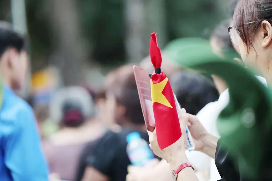Nhiều bạn trẻ mang theo cờ rủ, lặng lẽ xếp hàng. Ảnh: Minh Sơn/Vietnam+