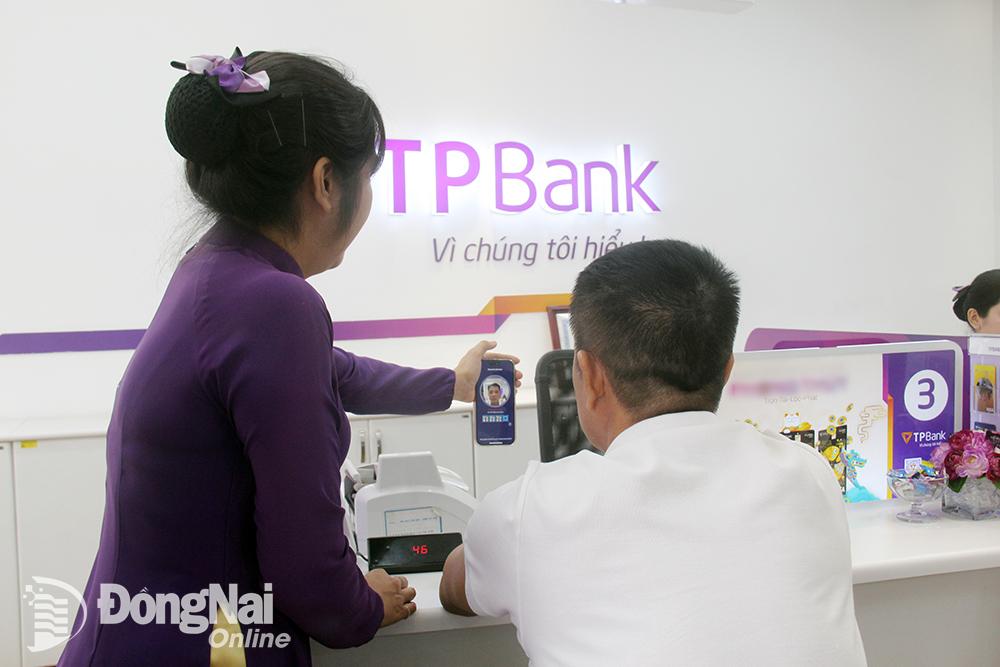 Nhân viên của ngân hàng TPBank chi nhánh Biên Hòa hỗ trợ khách hàng xác thực khuôn mặt. Ảnh: Hải Quân