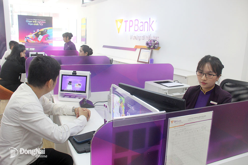 Nhân viên của ngân hàng TPBank chi nhánh Biên Hòa hỗ trợ khách hàng xác thực sinh trắc học thông qua thiết bị tích hợp. Ảnh: H.Hà