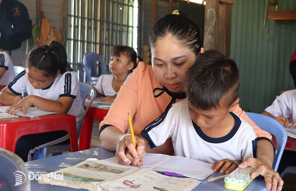 Chị Nguyễn Thị Kim Lan đang hướng dẫn trẻ em làng bè tập luyện viết chữ