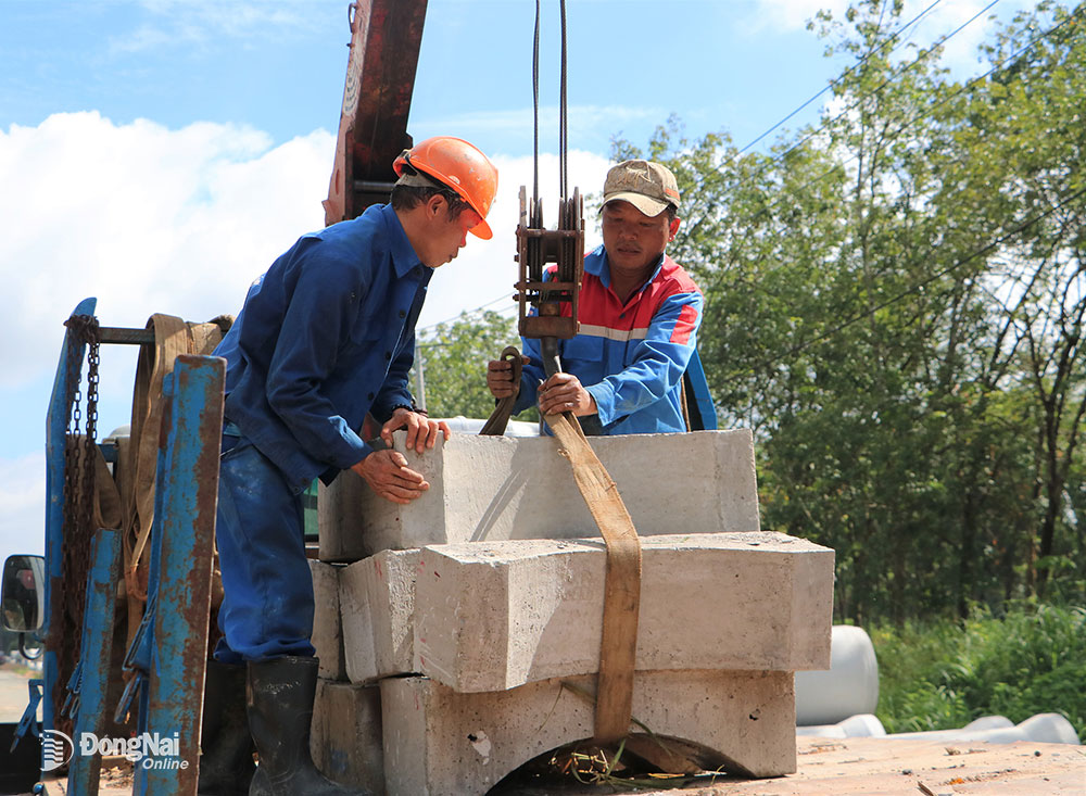 Công nhân vận chuyển các khối bê tông “đệm gối” phục vụ thi công hệ thống thoát nước của khu tái định cư.