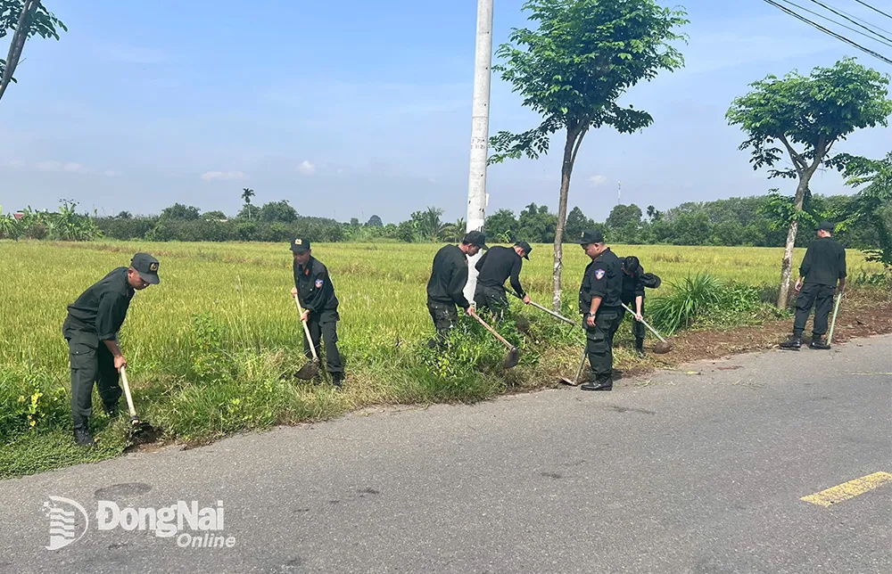 Các cán bộ, chiến sĩ Phòng Cảnh sát cơ động Công an tỉnh dọn vệ sinh tuyến đường nông thôn tại xã Thạnh Phú.