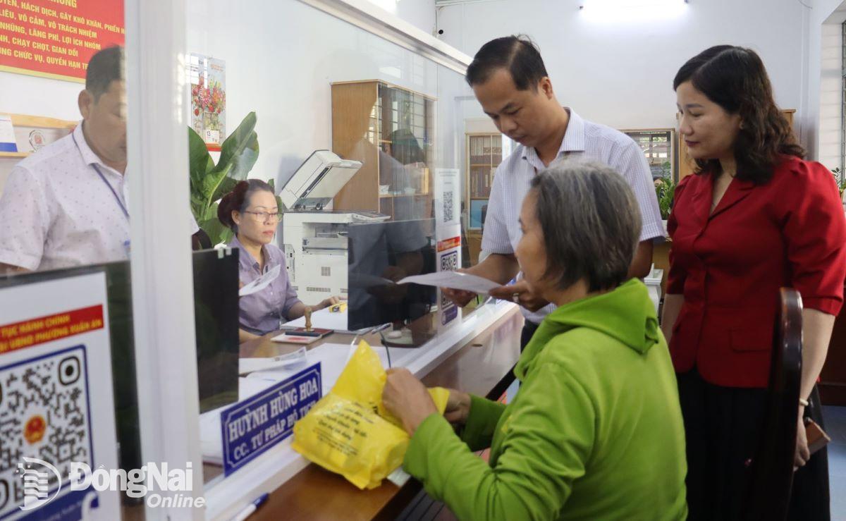 Lãnh đạo thành phố Long Khánh và phường Xuân An hướng dẫn người dân làm thủ tục hành chính trong mô hình “1 giờ buổi sáng vì dân”. Ảnh: Nguyệt Hà- Kim Chi