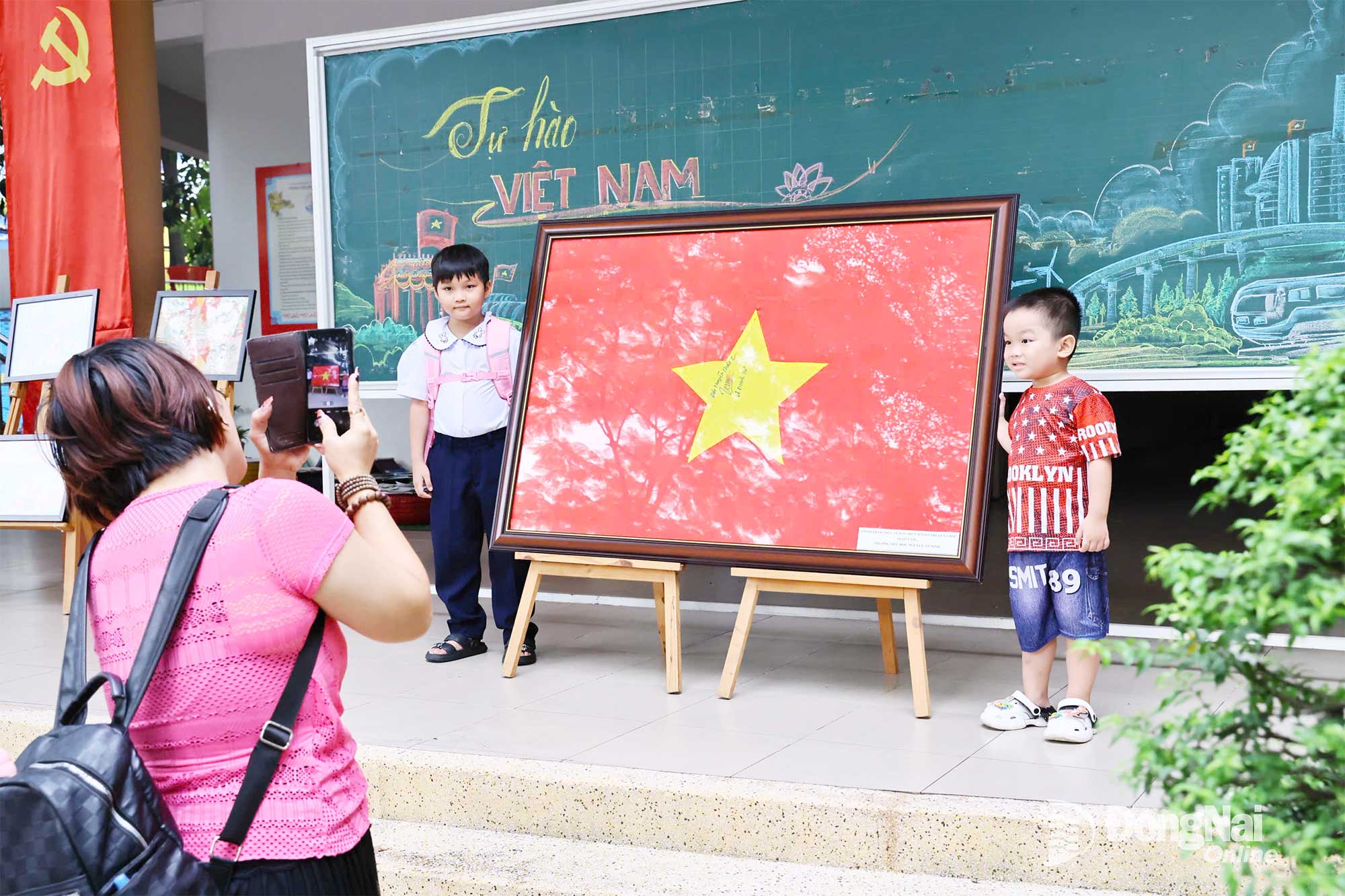 Parents take the opportunity to capture moments of their children standing by the national flag. Photo: Cong Nghia