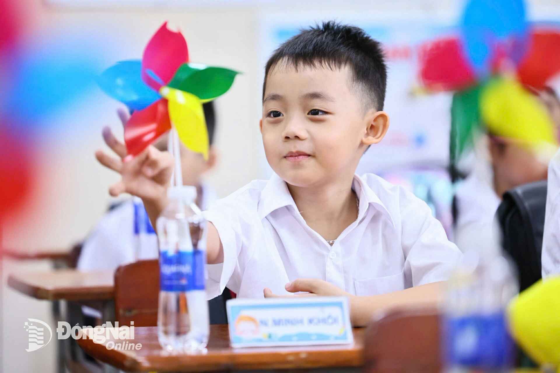 A first-grade student at Nguyen An Ninh Primary School (Tam Hiep Ward) is excited about a pinwheel gifted by their homeroom teacher on the first day of school