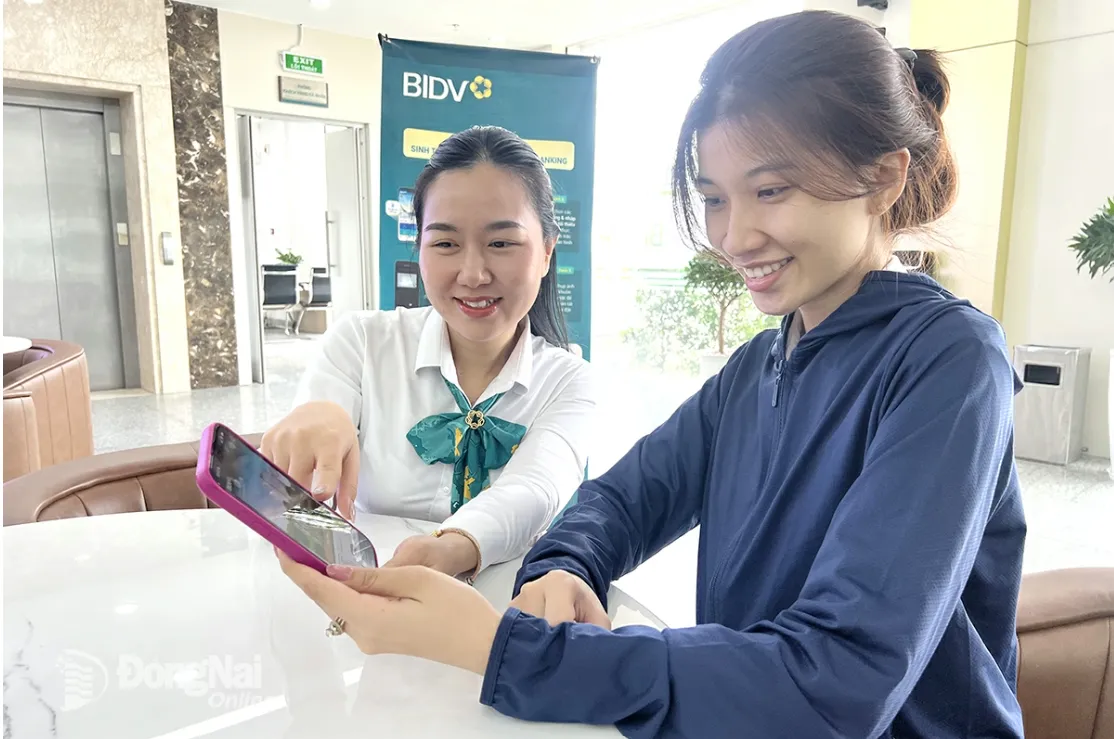 An employee of Bien Hoa-based BIDV (Tran Bien Ward) guides a customer how to use online utilities and services via the digital banking application. Photo: Hai Quan