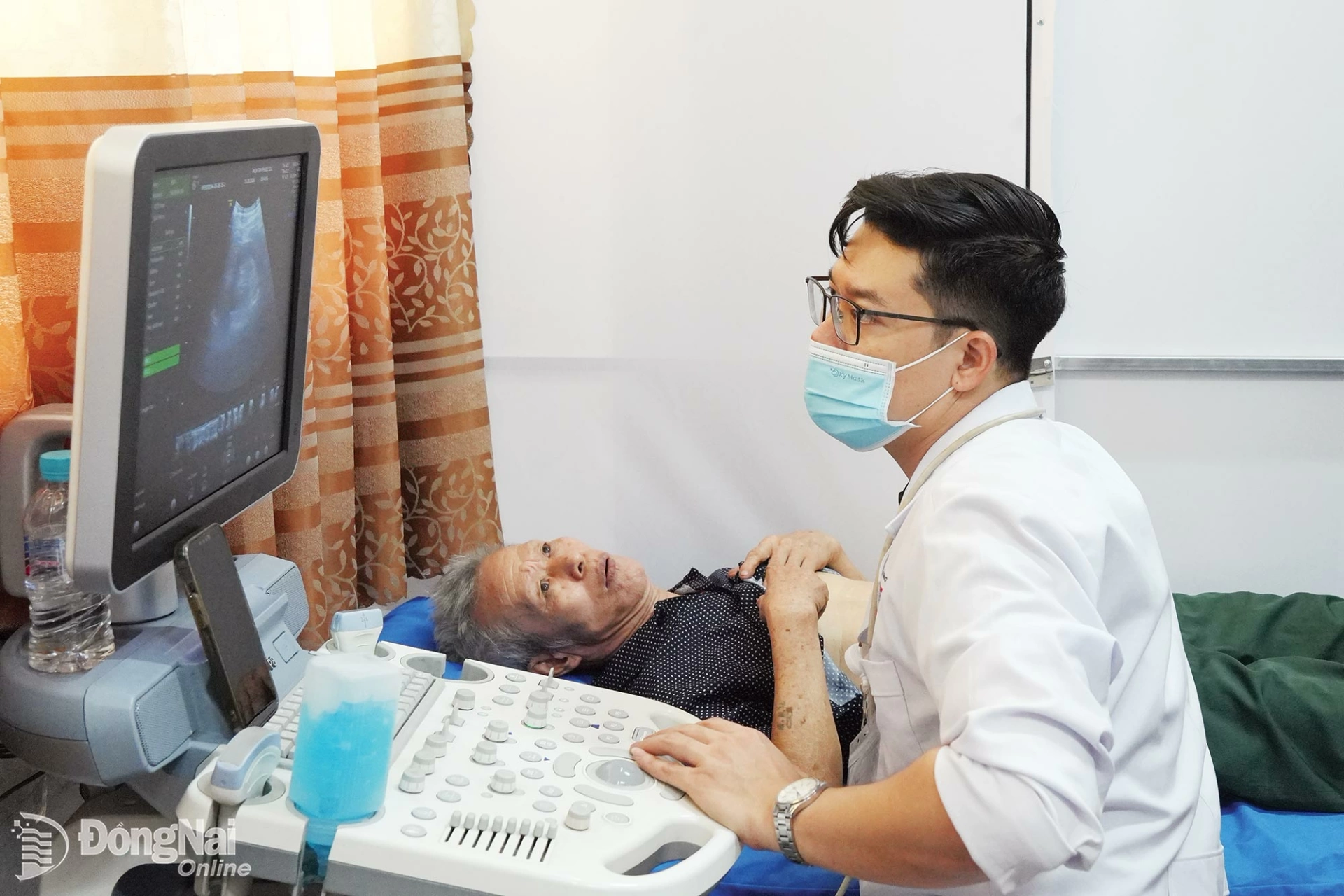 A doctor from Tam Phuoc General Clinic performs an abdominal ultrasound examination on an older resident during a free health screening program in Binh Minh commune. Photo: Bao Han