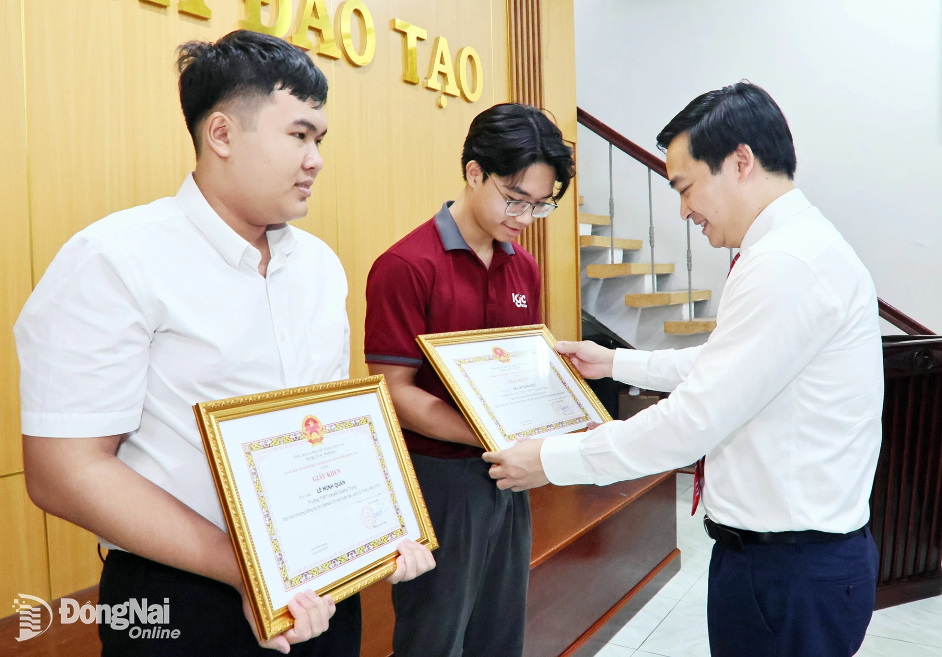 Dr. Dang Anh Tuan, Director of the Department of Education and Training, presents certificates of merit to two students who achieved outstanding results at international competitions. Photo: Cong Nghia

