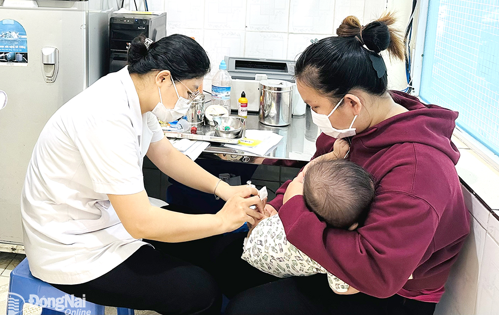 Phụ huynh đưa con đi tiêm vaccine dịch vụ tại Trung tâm Y tế huyện Long Thành.