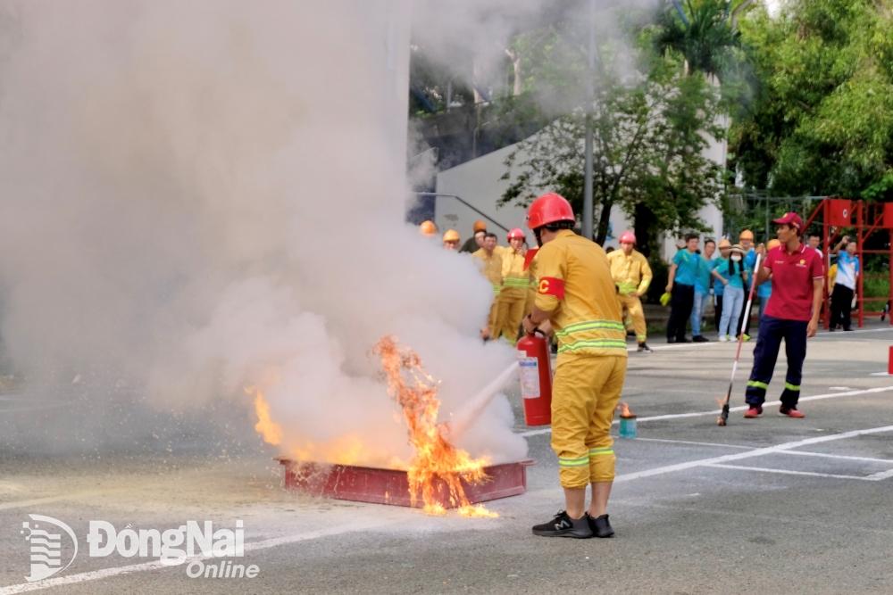 Các đội thi thực hiện nội dung dùng bình chữa cháy dập tắt đám cháy khay xăng. Ảnh: Minh Thành