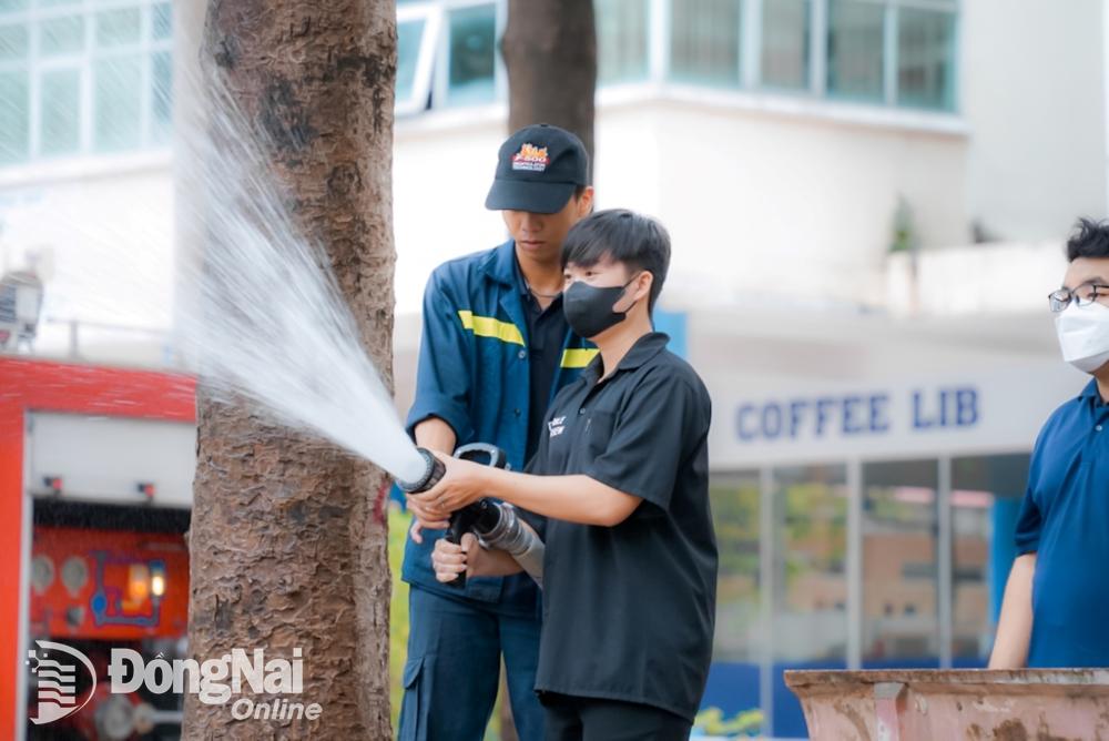 Cảnh sát phòng cháy, chữa cháy hướng dẫn sinh viên sử dụng vòi nước chữa cháy. Ảnh: Lê Duy