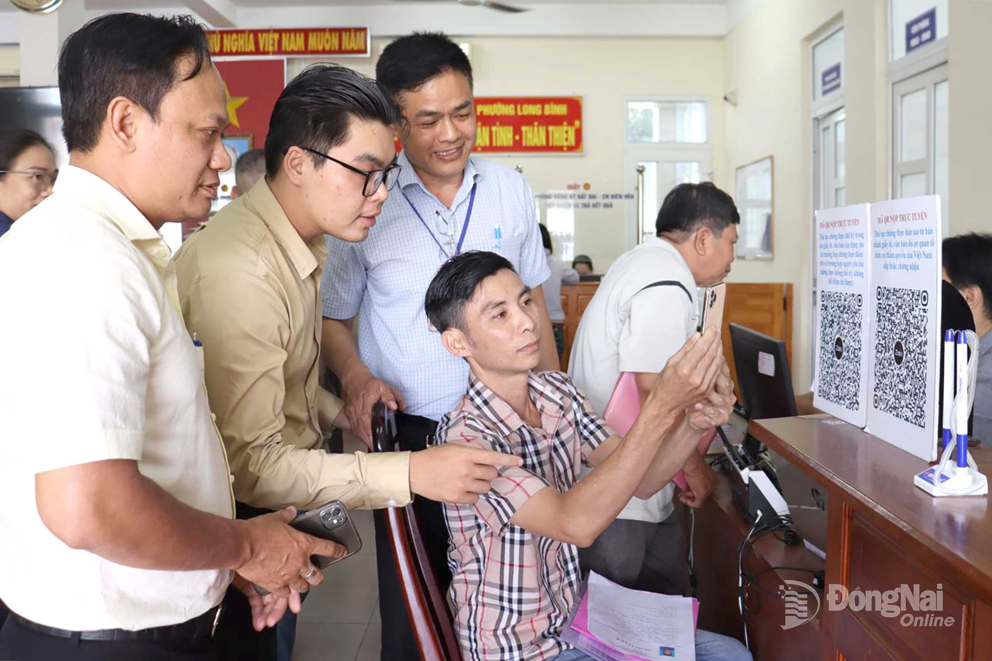 Official at Long Binh ward PASC in Dong Nai province guide residents in making online payments via QR code scanning. Photo: Nguyet Ha