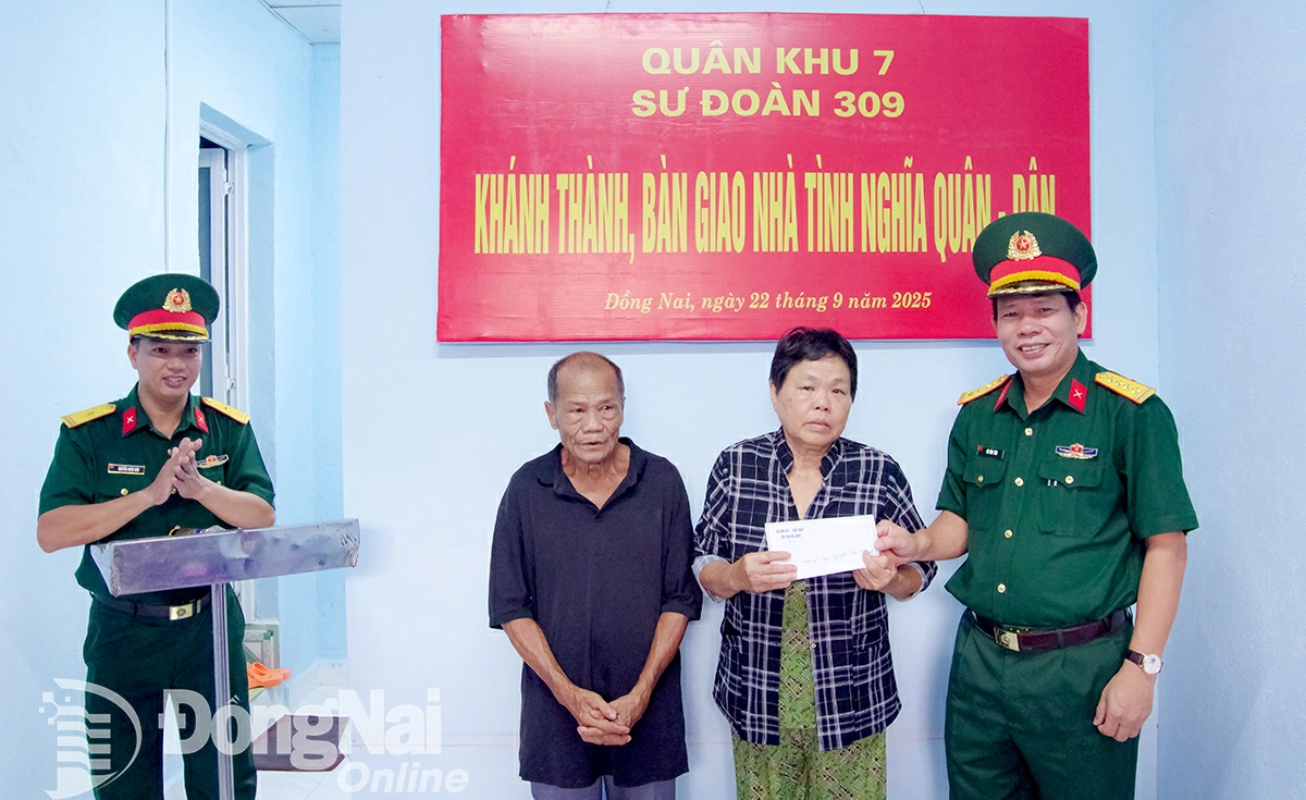 Đại tá Vũ Văn Tám, Bí thư Đảng ủy, Chính ủy Sư đoàn 309 tặng quà gia đình ông Nguyễn Văn Chánh. Ảnh: Nguyễn Hùng