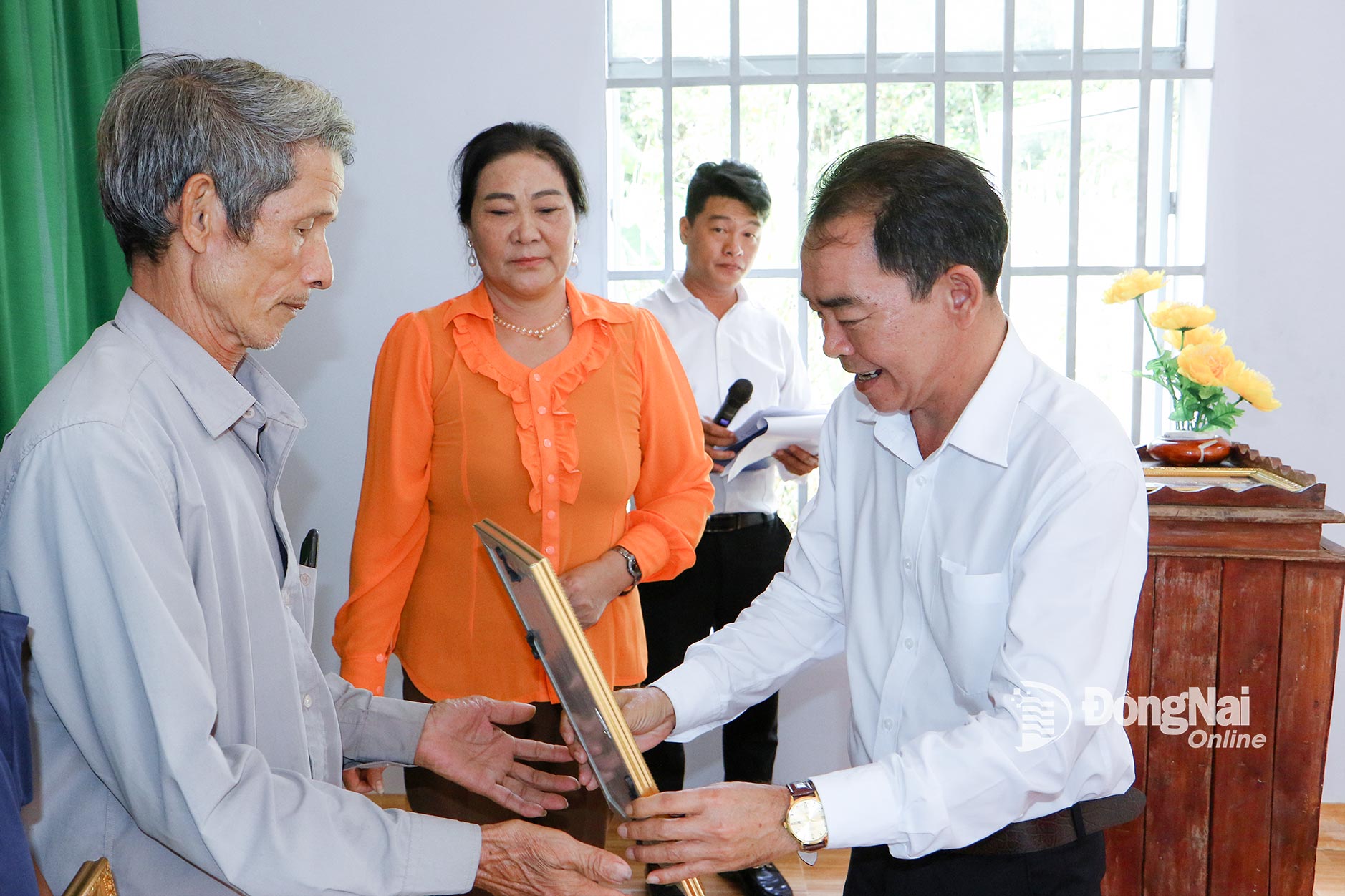 Party Secretary and Chairman of the People’s Council of Dak Lua commune Phan Van Tung hands over the decision to grant a permanent house to a resident during the first communal VFF Congress for the 2025–2030 tenure. Photo: Van Truyen


