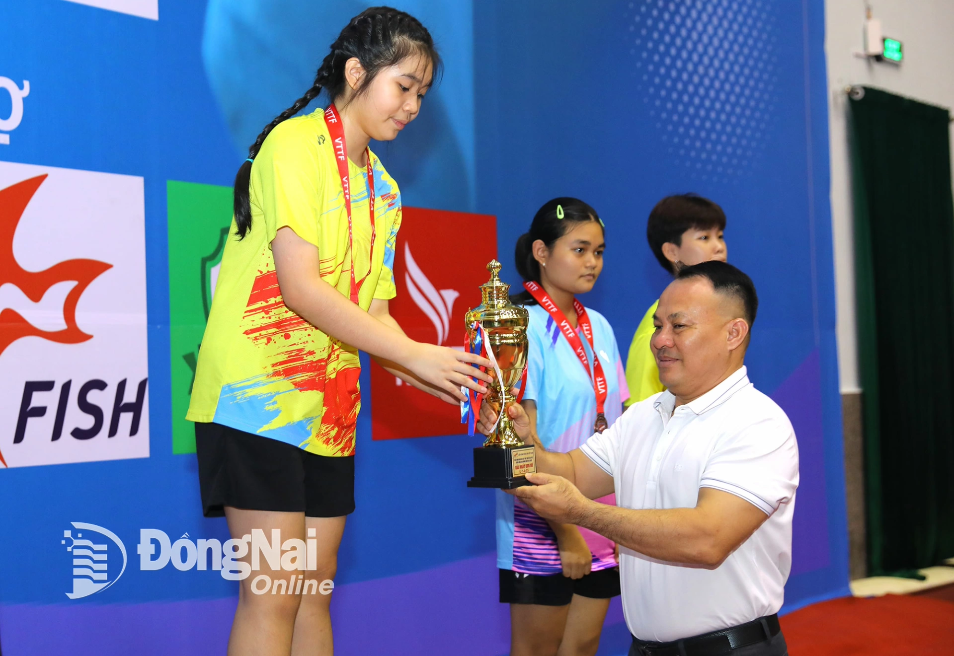 Bui Anh Vu, Director of the Provincial Sports Training and Competition Center, presents the womens singles 14-15 age group championship cup to athlete Le Hoang Linh Dan. Photo: Huy Anh