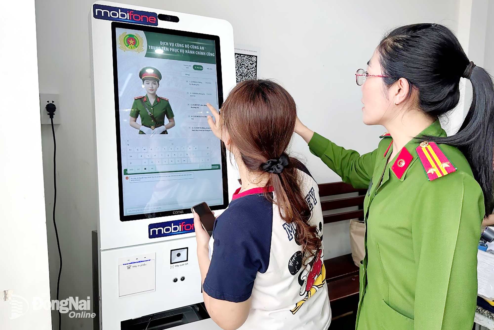 Cán bộ Công an phường Trảng Bom hướng dẫn người dân sử dụng AI Kiosk tra cứu thủ tục hành chính. Ảnh: C.T.V