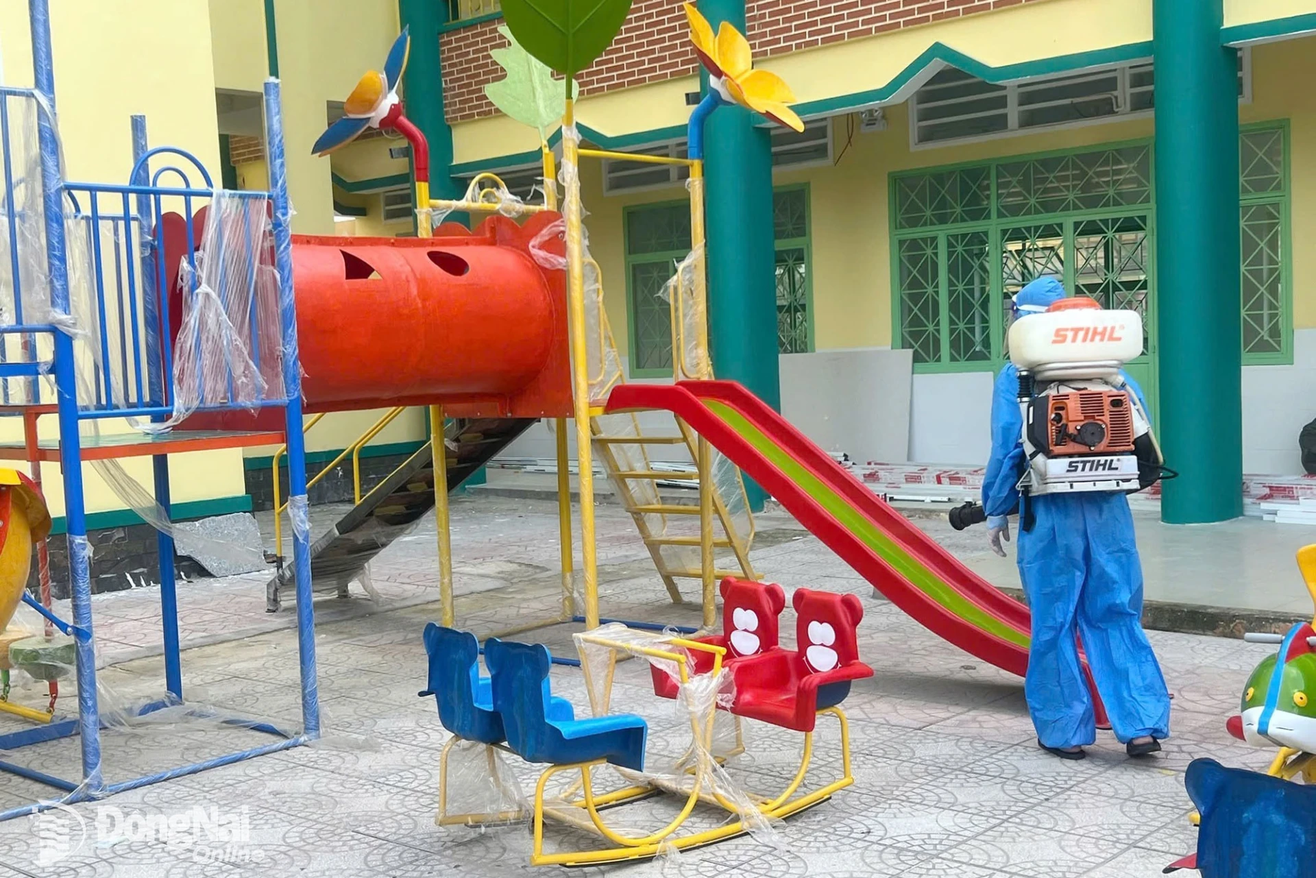 Nhân viên Trạm Y tế phường Dầu Giây phun xịt thuốc phòng, chống sốt xuất huyết tại điểm Trường mầm non Sơn Ca. Ảnh: Nhật Quang