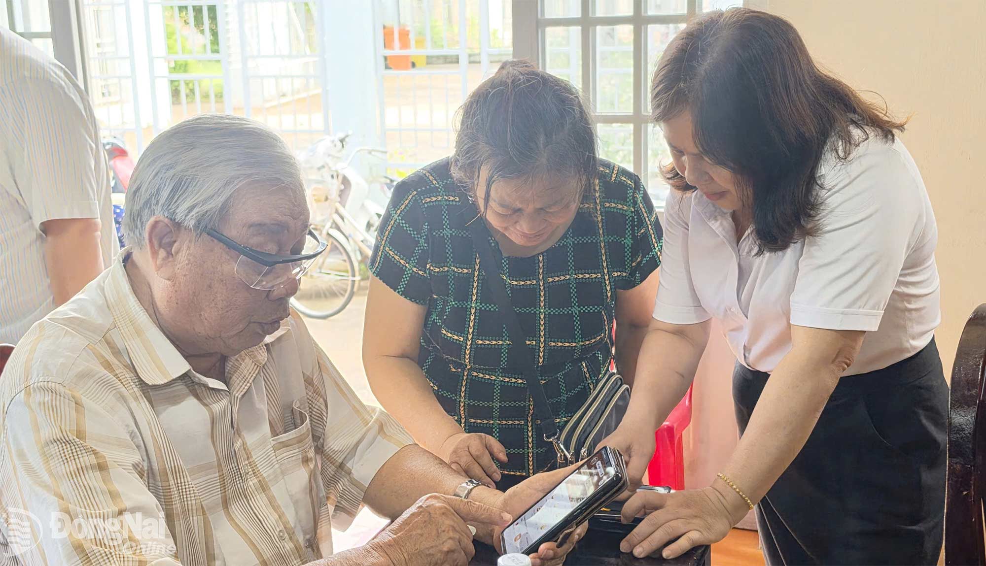 Cán bộ Trung tâm Phục vụ hành chính công phường hướng dẫn người dân các thao tác trên điện thoại. Ảnh: Trần Thành