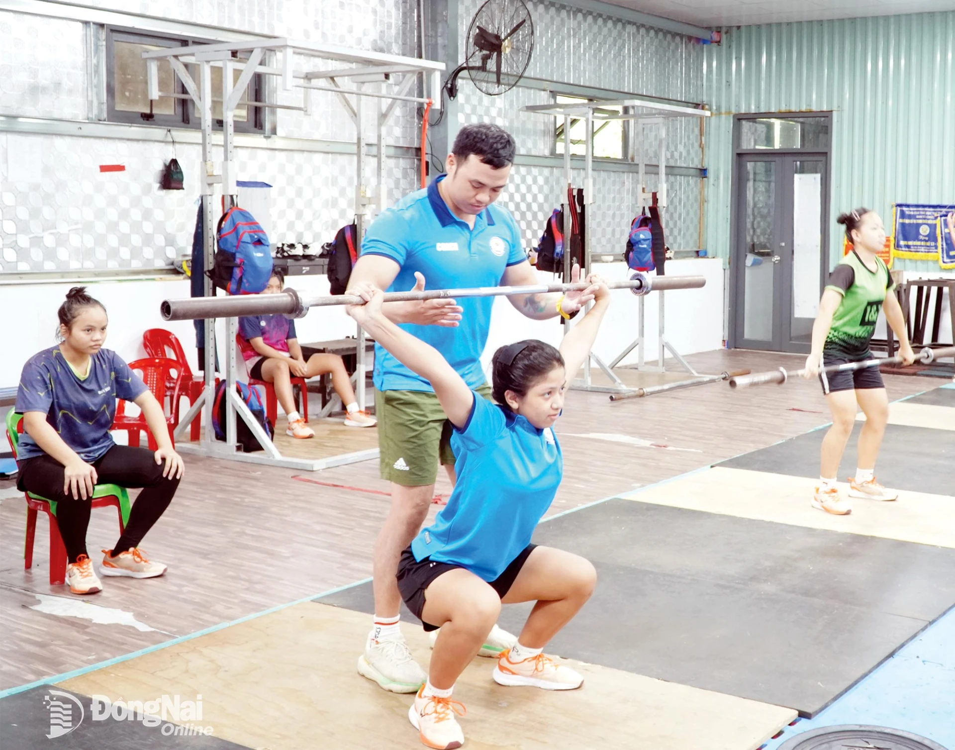 Huấn luyện viên hướng dẫn vận động viên cử tạ 
chống đỡ ngồi sâu, hỗ trợ động tác giật.
