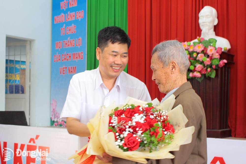 Chánh Văn phòng Tỉnh ủy Viên Hồng Tiến tặng hoa cho đảng viên Trần Xuân Dương sinh hoạt tại Chi bộ KP.Hương Phước, TP.Biên Hòa được nhận Huy hiệu 75 năm tuổi Đảng 