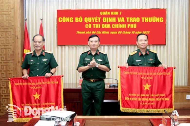 Trung tướng Trần Hoài Trung thừa ủy quyền của Thủ tướng Chính phủ trao Cờ thi đua xuất sắc cho Sư đoàn 302 (bìa phải) và Cục Chính trị Quân khu 7 (bìa trái)

