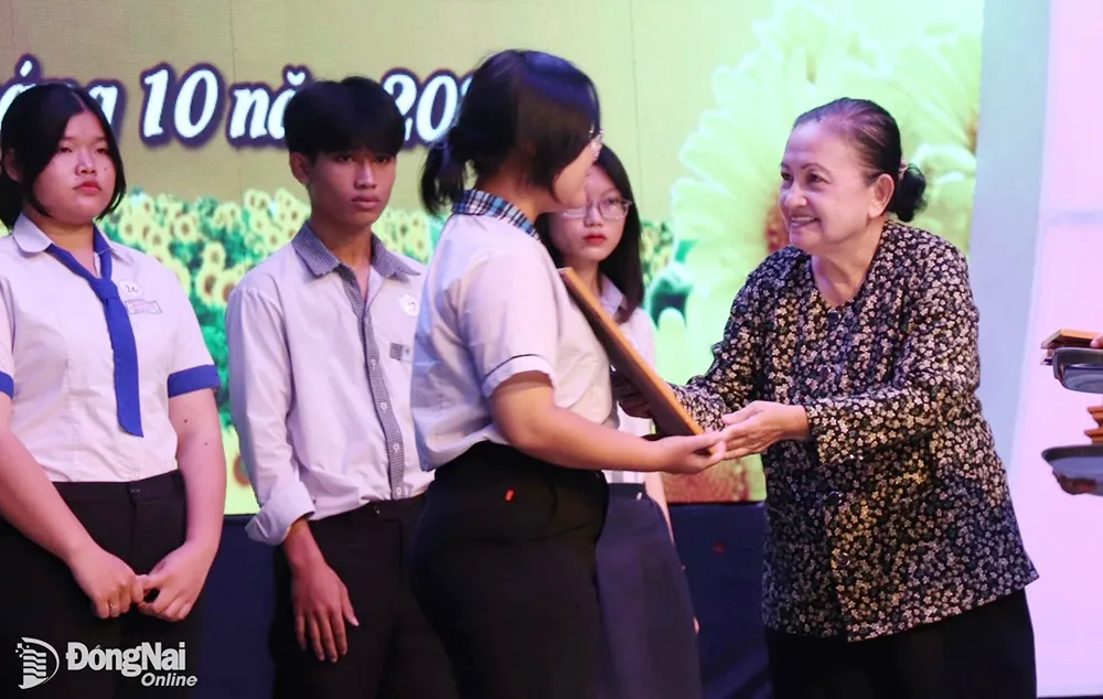 Đại diện gia đình đồng chí Lê Đình Nhơn trao học bổng cho các học sinh