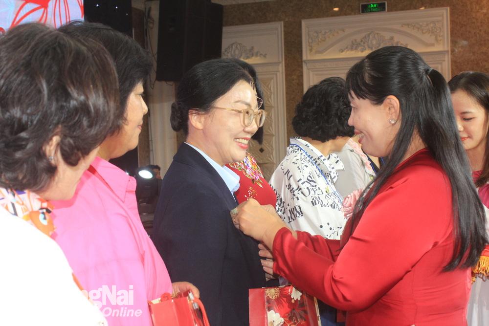 Chủ tịch Hội LHPN tỉnh Lê Thị Thái cài huy hiệu của Hội LHPN Việt Nam lên áo các thành viên Đoàn Hiệp hội phụ nữ tỉnh Gyeongnam