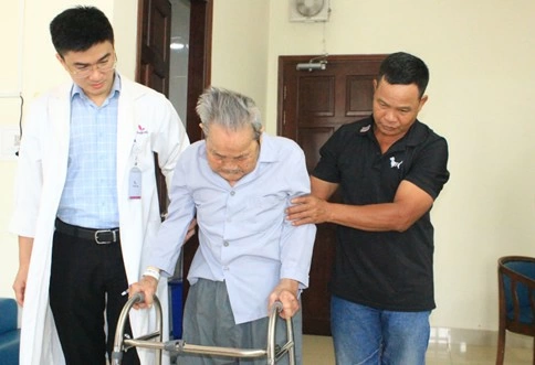 Cụ ông được bác sĩ và người nhà hỗ trợ tập đi lại sau ca phẫu thuật. Ảnh: Hoàn Lê