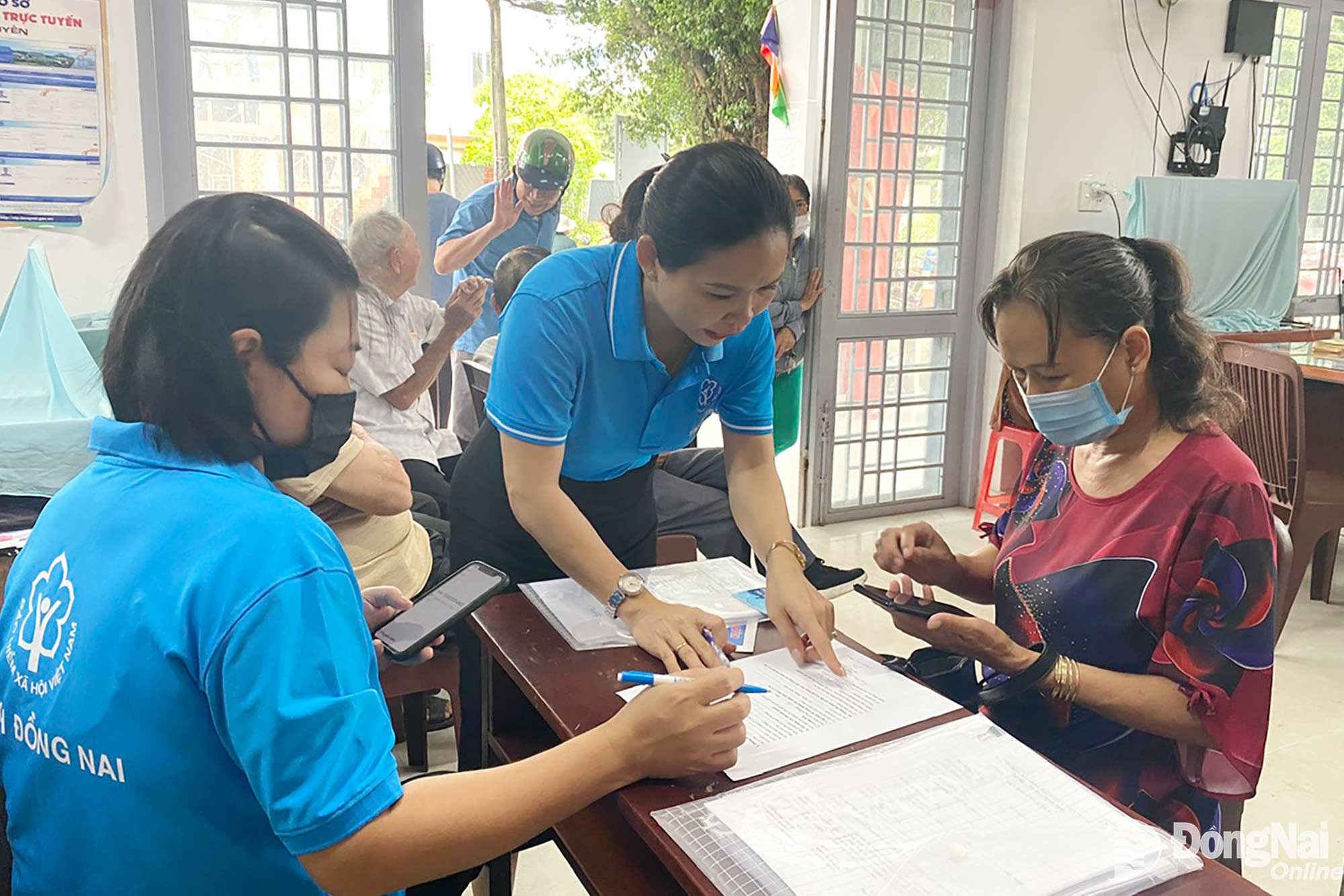 Nhân viên Bảo hiểm xã hội thành phố hướng dẫn người dân phường Trấn Biên làm thủ tục nhận lương hưu. Ảnh: C.T.V


