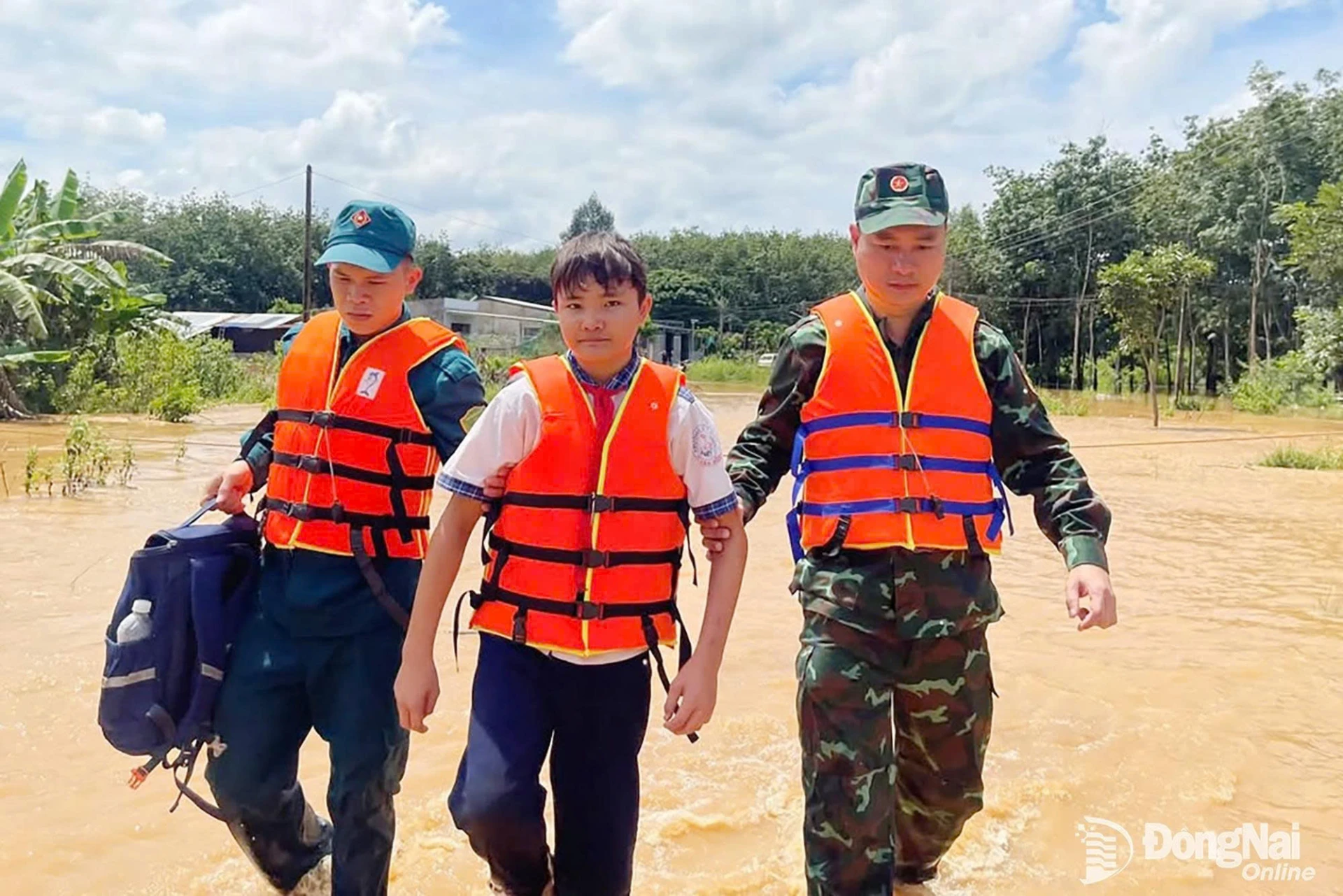 Officers and soldiers of the Binh Phuoc Ward Military Command help transport a student through flooded areas.