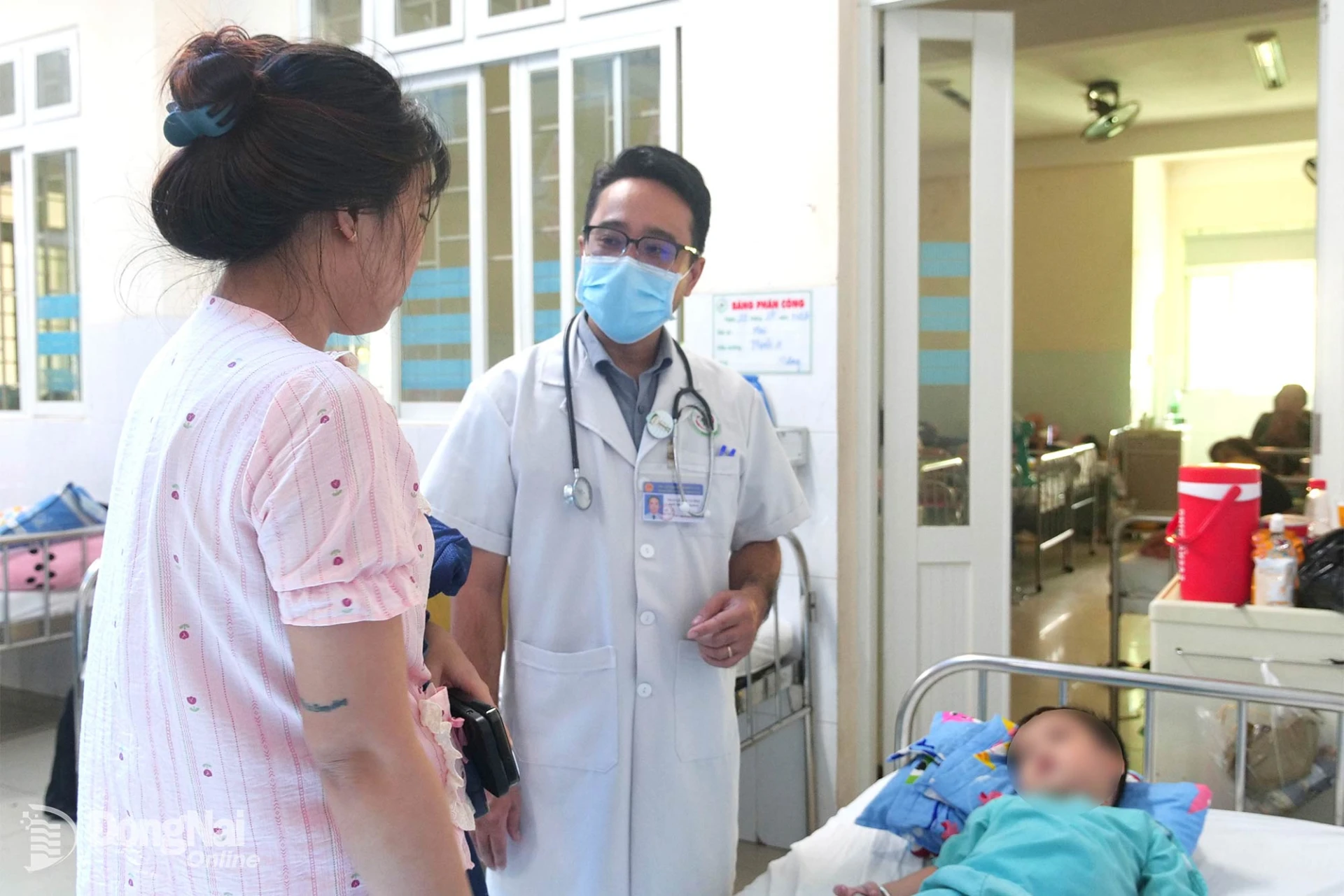 Thạc sĩ, bác sĩ Trần Lê Duy Cường, phụ trách Khoa Hô hấp, Bệnh viện Nhi đồng Đồng Nai thăm khám cho bệnh nhi và hướng dẫn phụ huynh cách chăm sóc trẻ. Ảnh: Hạnh Dung