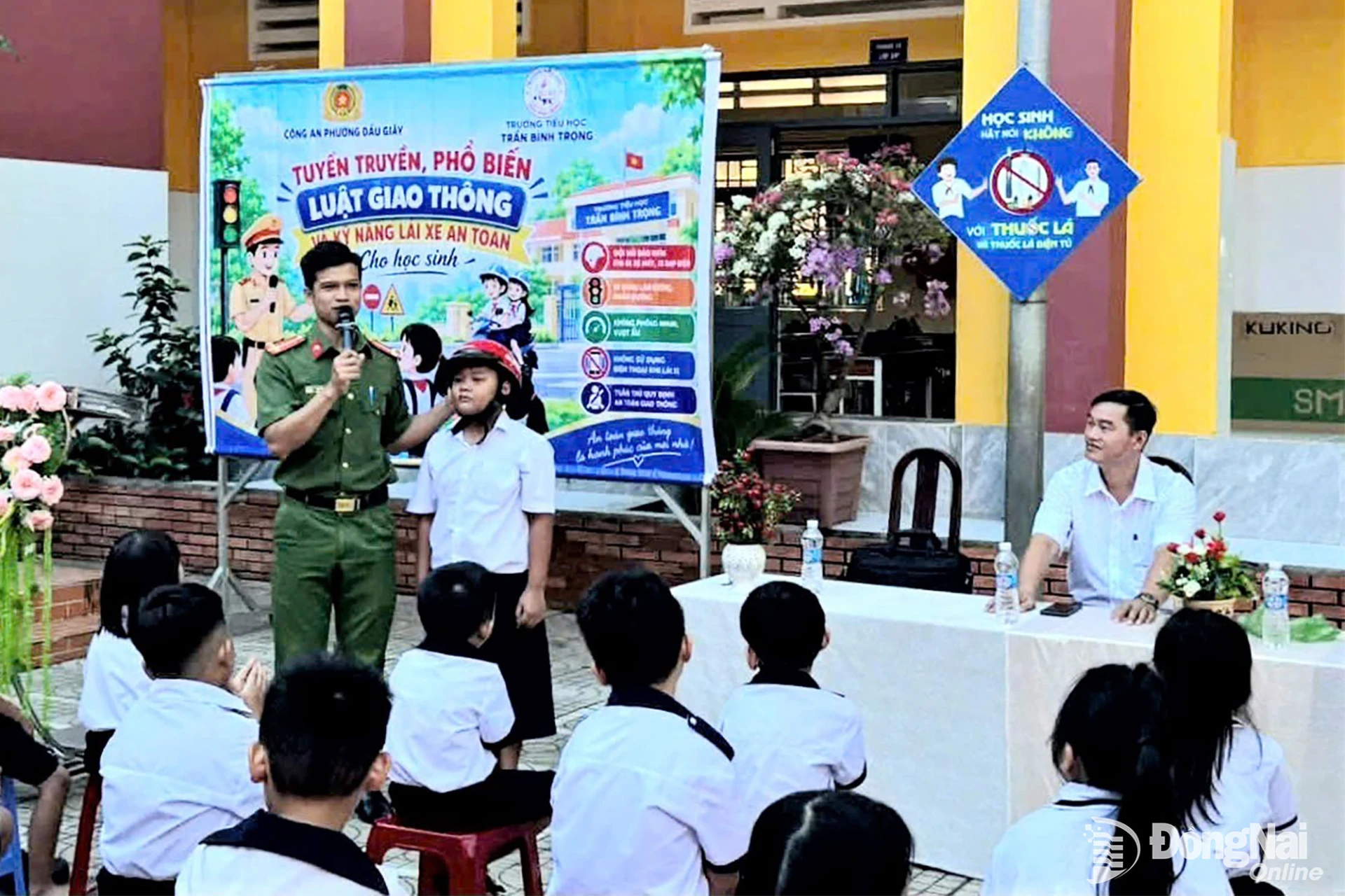 Cán bộ Công an phường hướng dẫn học sinh đội mũ bảo hiểm an toàn, đúng cách. Ảnh: Nhật Quang

